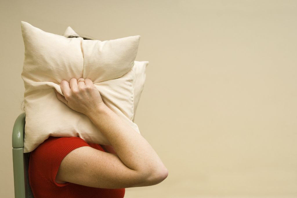 woman covering head with a pillow