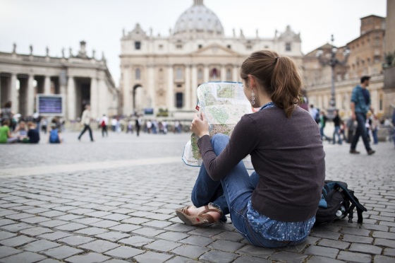 Pretty young female tourist studying a map at St. Peter's square