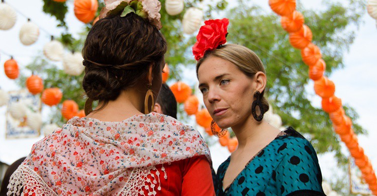 Dos mujeres vestidas de sevillanas charlan en la Feria. Sandra Vallaure (Flickr)