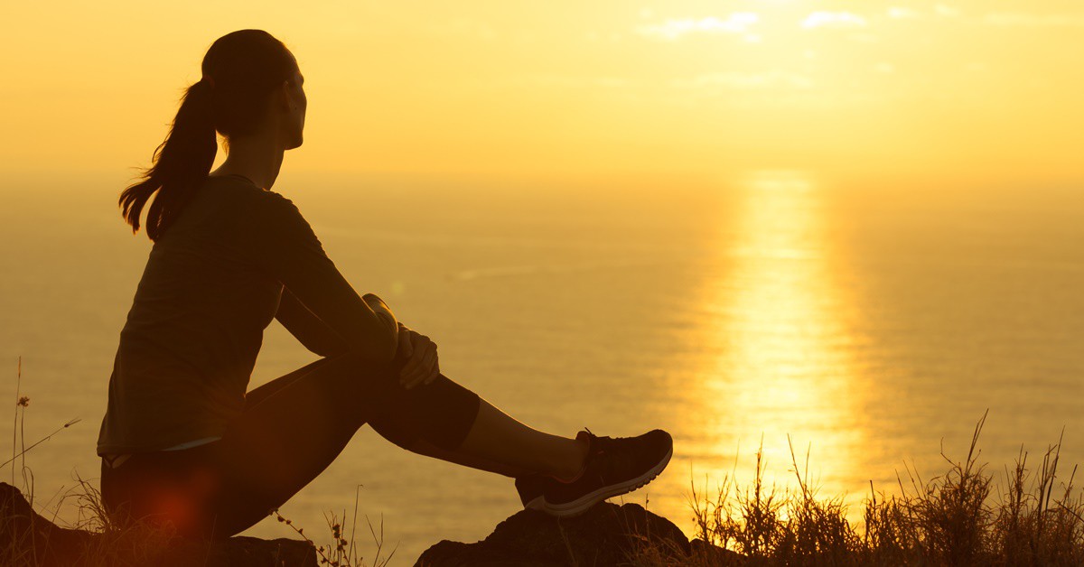 Mujer sola viendo una puesta de sol. Kieferpix (iStock)