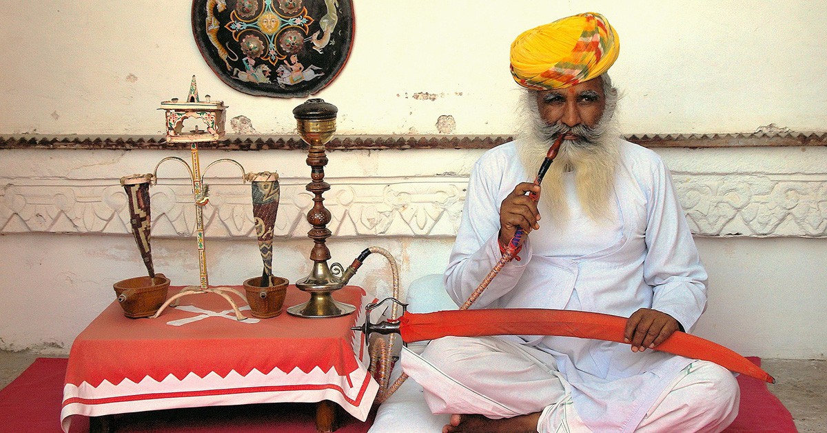 Un hombre sin con turbante, sentado y fumando