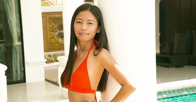 Una mujer tailandesa con un bikini rojo apoyada en una columna