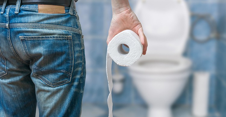 Un nombre sujeta un rollo de papel higiénico en el baño