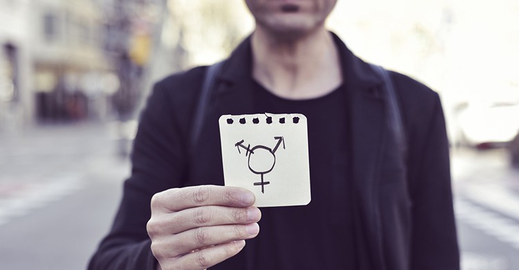Un hombre sostiene un papel con el dibujo de un símbolo LGTB