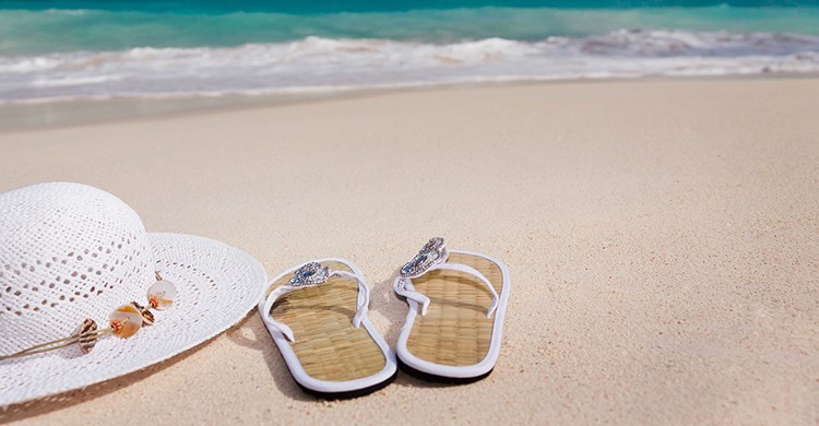 Chanclas y sombrero en la playa