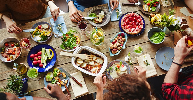 Una mesa de comida con personas a su alrededor