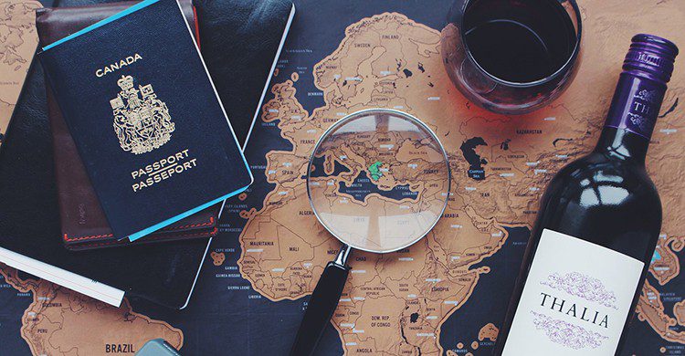 Un mapa, un pasaporte, una botella de vino y una lupa