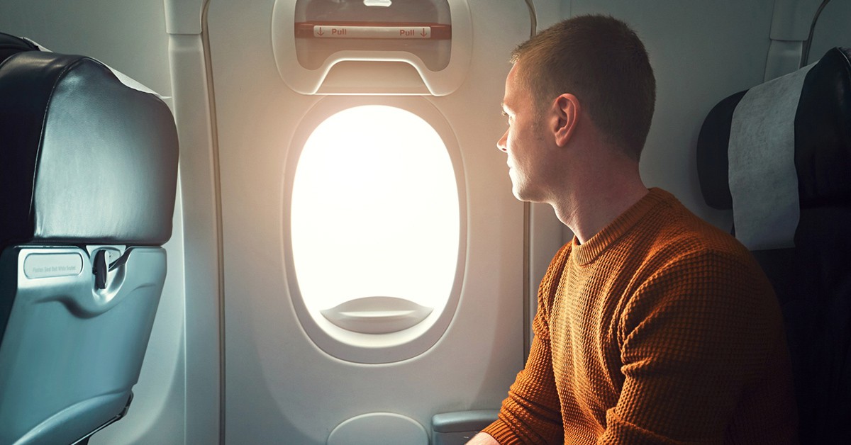 Un hombre sentando al lado de la ventanilla del avión