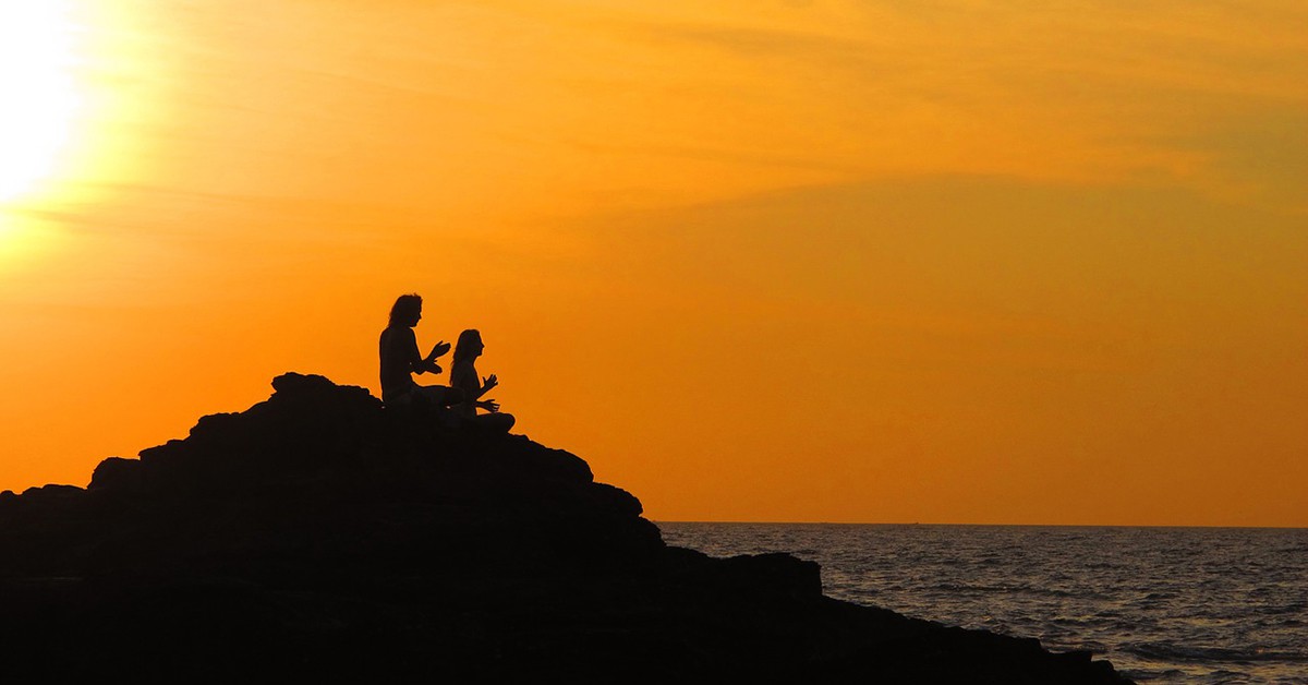 Dos personas hacen yoga al atardecer en Goa