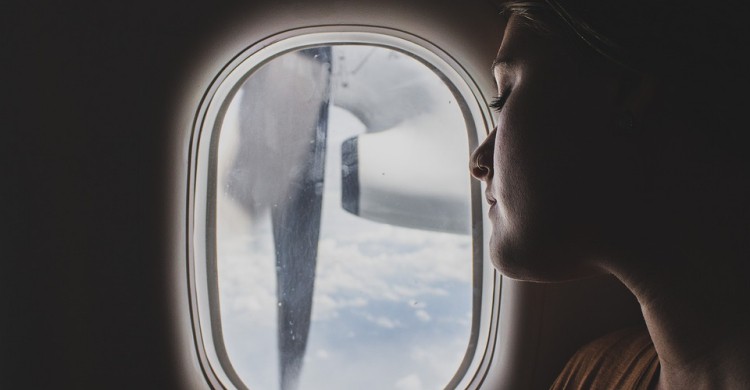 Una mujer mira el motor de un avión a través de la ventanilla