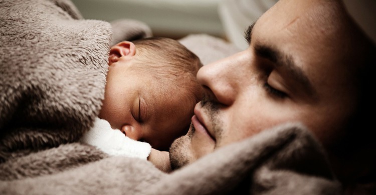 Un padre duerme junto a su bebé