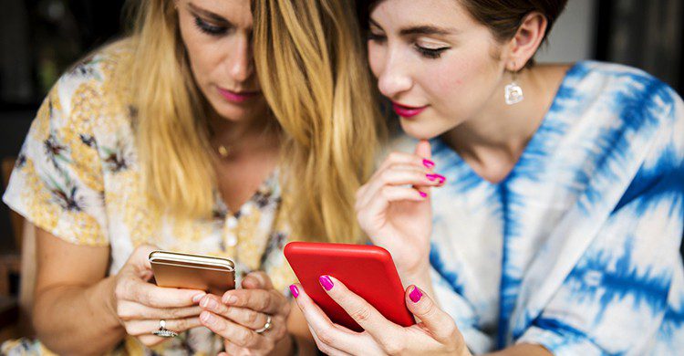 Dos chicas miran sus celulares