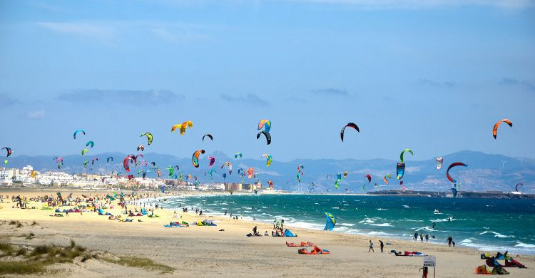 Gente practicando windsurf en la playa de Tarifa. (AdobeStock)