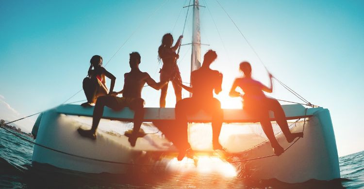 Grupo de amigos en un catamarán en Ibiza, España. (AdobeStock)