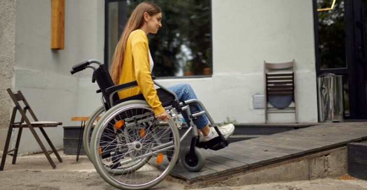 Mujer entrando en una cafetería por la rampa adaptada para personas con movilidad reducida. (Envato Elements)