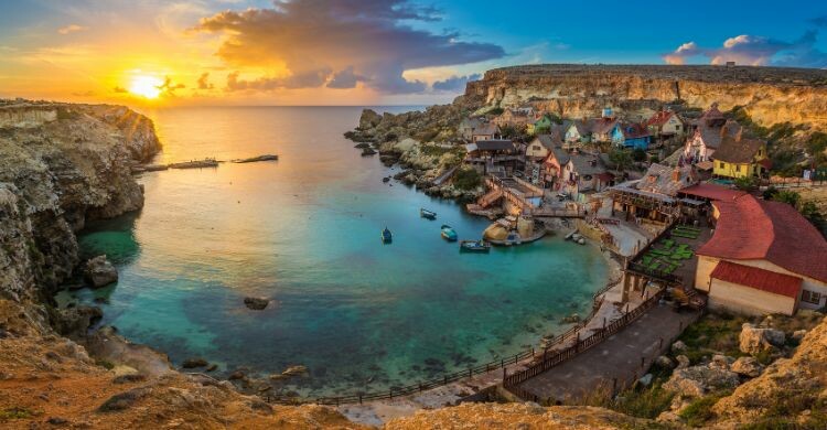 Vista del horizonte del famoso pueblo de Popeye con barcos tradicionales Luzzu, en Malta. (Adobe Stock)